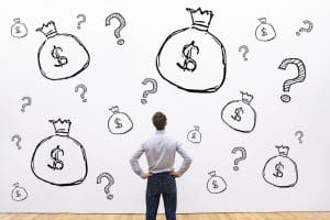 Man looking at a wall with money bags and question marks, deciding on the cheapest personal loan in Singapore